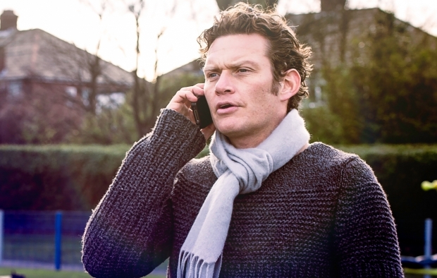 An image of a man talking on the phone in a park
