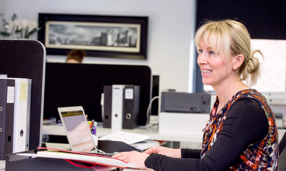 An image of a woman working at a desk in an office