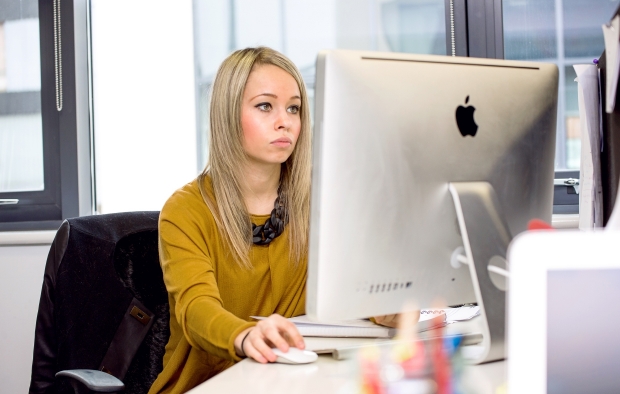 An image of a young woman working on  an iMac computer