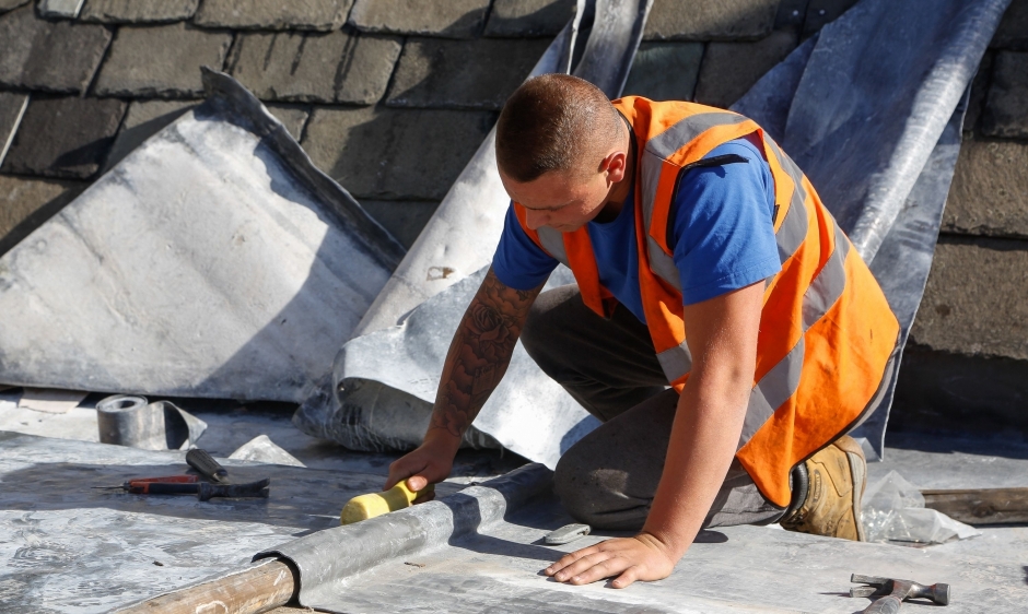 An image of a roofer in a high vis vest working on a roof