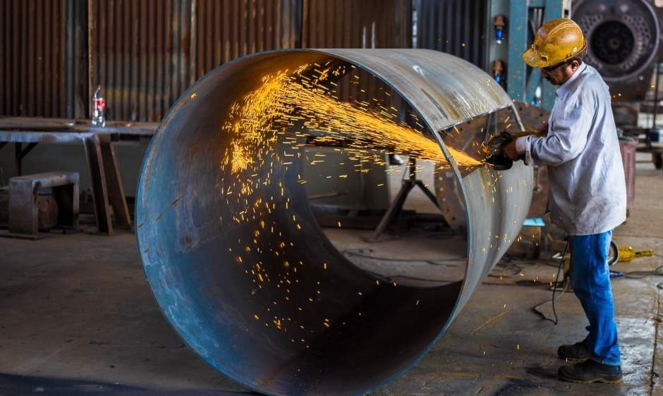 An image of a man working in an industrial setting using an angle grinder