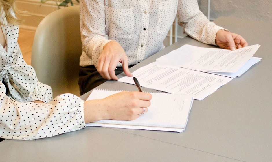 A close up image of two women signing paperwork