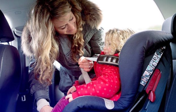 An image of a woman putting her child in a car seat