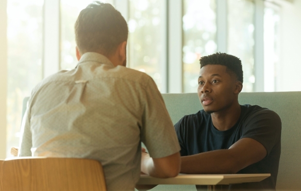 An image of two men sitting across from one another at a table