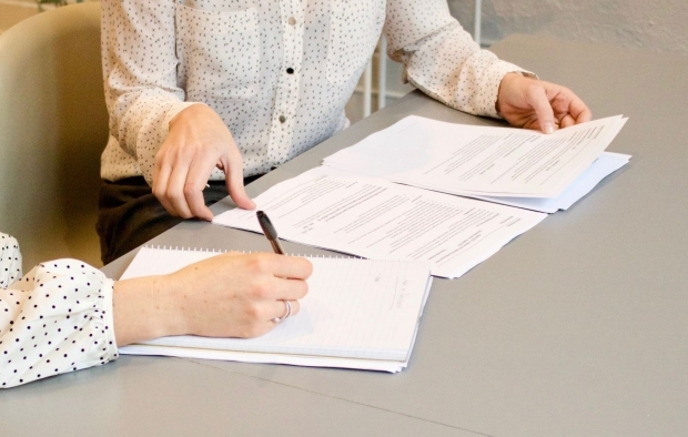 A close up image of two women signing paperwork