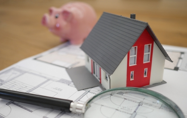 A small replica house next to a piggy bank
